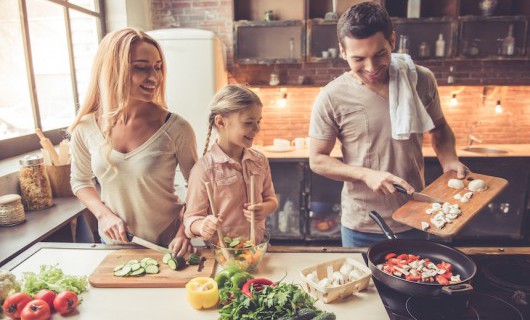 A girl and her parents are preparing a variety of vegetables for a healthy meal.