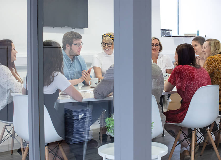 The Social Change UK team playfully discuss ideas in the meeting room.