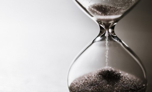 Close up of a glass hour glass, with sand falling through.